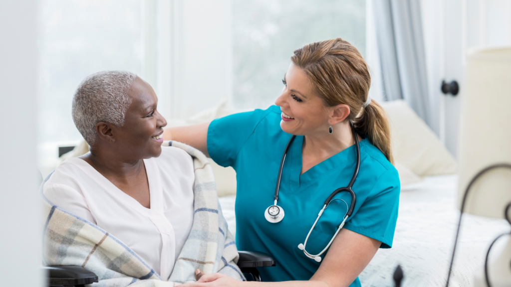 A woman in a wheelchair smiles at a health care professional who kneeled down to be eye level